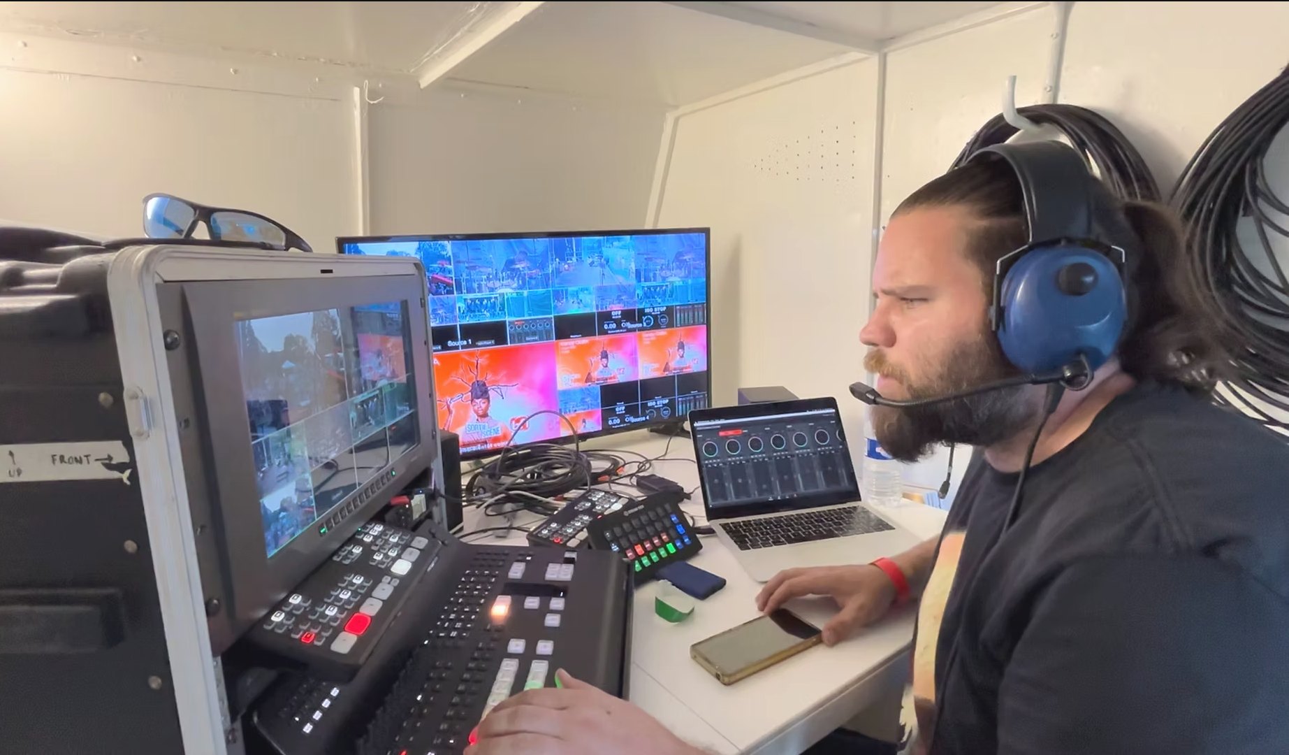 Réalisateur en régie mobile, casque intercom, main sur le mélangeur, multiview Sortie de Scène à l'écran